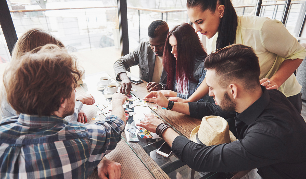 Group of young adults playing a game around a table