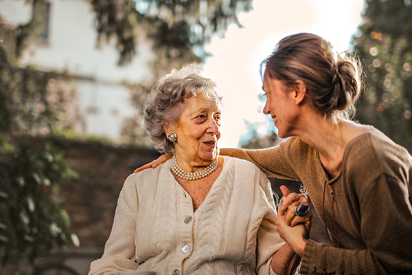 Woman smiling while holding elderly woman's hand